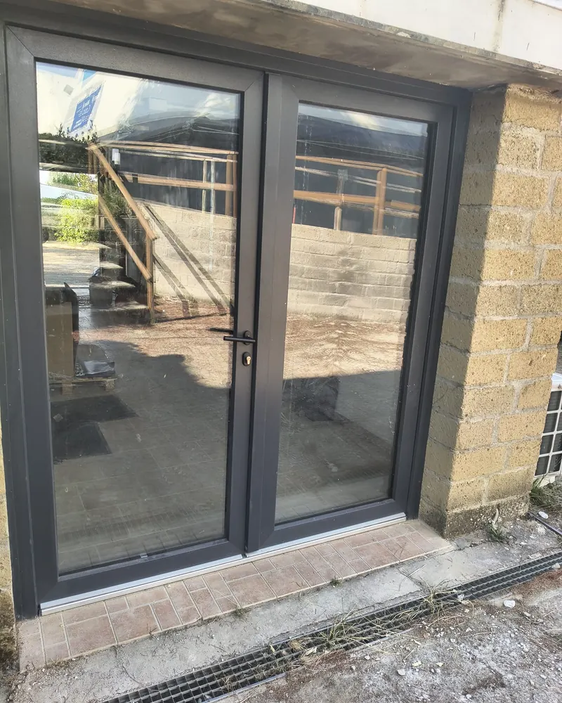 Portafinestra a due ante in PVC grigio antracite vista dall’esterno, con soglia ribassata in alluminio