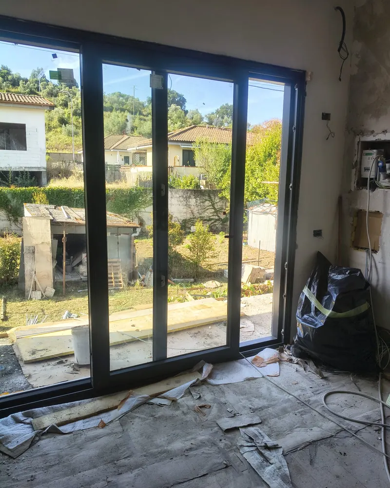 Scorrevole in alluminio antracite a tre ante in un cantiere, affaccio sul giardino