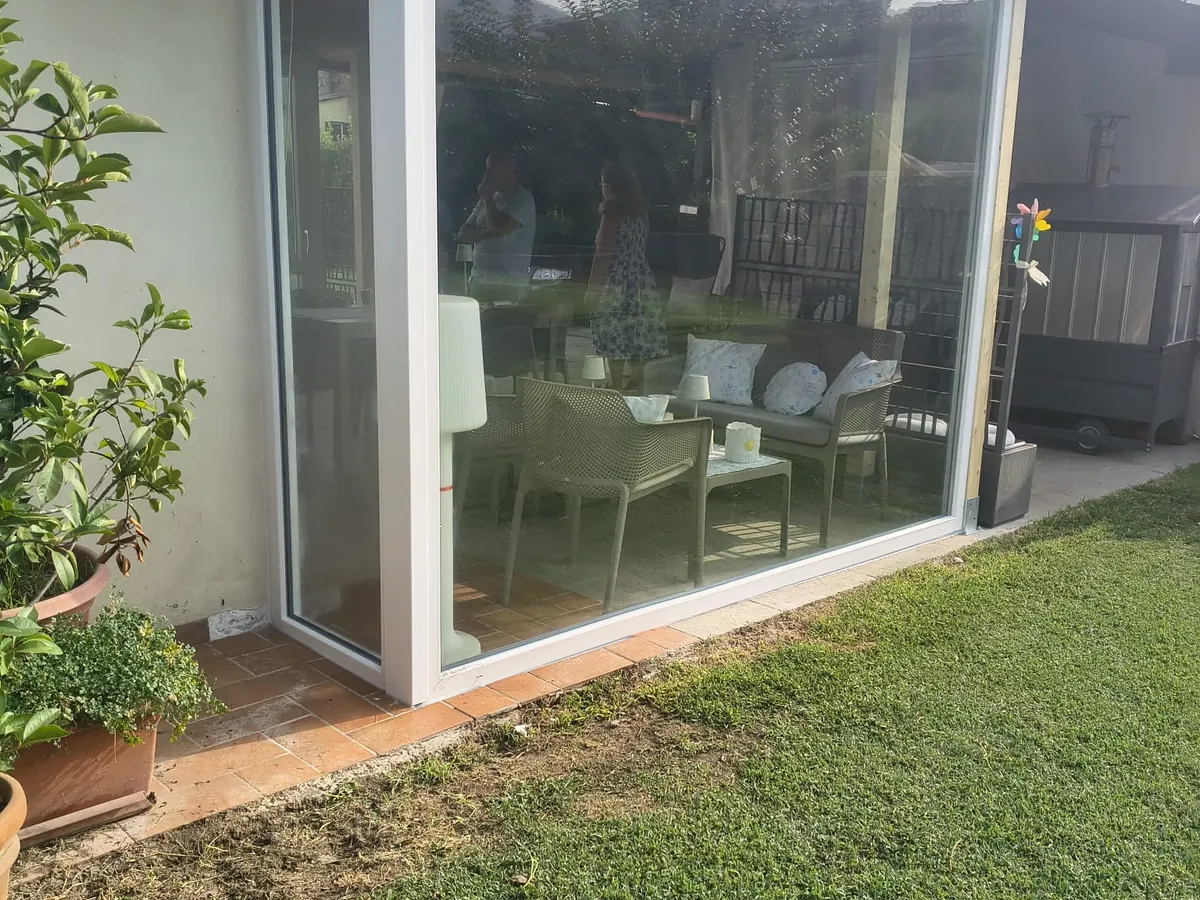 Grande vetrata fissa bianca su una veranda affacciata sul giardino